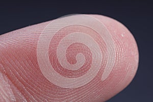 Finger with friction ridges on dark background, macro view