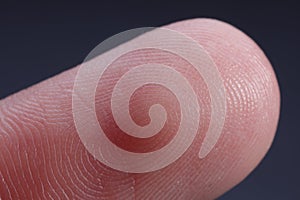 Finger with friction ridges on dark background, macro view