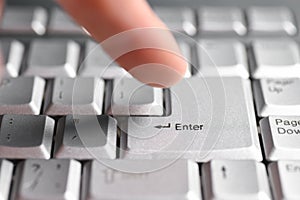 Finger hand presses the Enter button on the keyboard, close-up