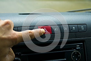 Finger hitting car emergency red light button in the car