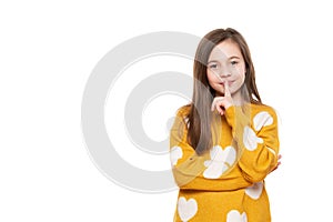 Finger on lips, silent gesture. Shhh! Waist up portrait of a charming young schoolgirl showing silence symbol. photo