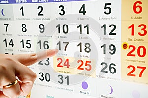Finger pointing at day of week on calendar