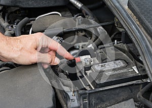 Finger pointing at positive car battery terminal