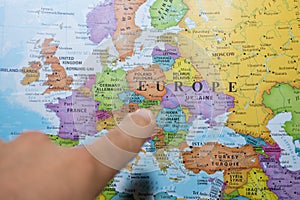 Finger pointing to a colorful country map of Europe deciding which country to vacation and travel