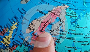 Finger pointing to the country of Sweden on a Globe photo