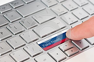 A finger press button with Russian flag on laptop keyboard and inscription fake news