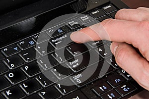 Finger presses the backspace key, laptop and hand