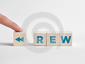 Finger presses the rewind REW button on wooden cubes photo