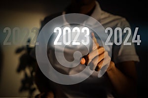 Finger pressing blue start 2023 button on virtual interface on gray background with copy space for text. Concept of new