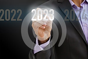 Finger pressing blue start 2023 button on virtual interface on gray background with copy space for text. Concept of new