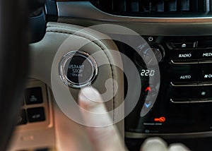 Finger pressing button the start button, stop the engine in the luxury car. The man's finger is pressing down. Owner and