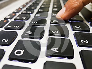 A finger pressing the D key on an keyboard on a laptop