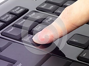 Finger pressing Delete button on the black keyboard