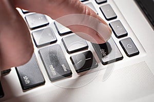 Finger is pressing delete key of computer keyboard, close up, top view