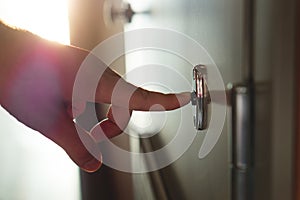 Finger pressing doorbell in sunny apartment building photo