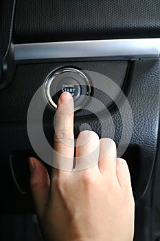 Finger pressing engine start button on car