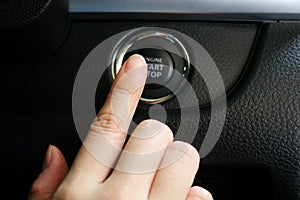 Finger pressing engine start button on car