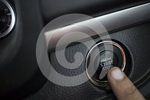 The Finger pressing the Engine start stop button of a car