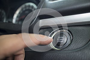 The Finger pressing the Engine start stop button of a car