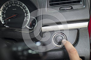 The Finger pressing the Engine start stop button of a car