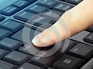 Finger pressing Enter button on the black keyboard