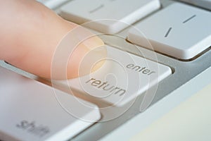 Finger is pressing enter key of a computer keyboard