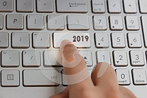 Finger pressing keyboard key written 2019 new year on laptop