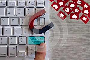 Finger pressing keyboard with text Social Media Marketing and magnet attract like, love and comment icon