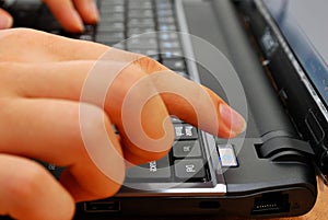 Finger pressing power button on laptop