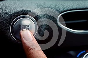 Finger pressing push to start ignition for a luxury vehicle.