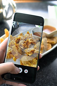 Finger pressing on smartphone for photograph chinese food in res