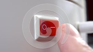 A finger pushes the red switch to the on position.