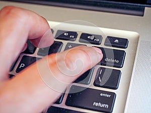 Finger pushing delete button on a keyboard of computer