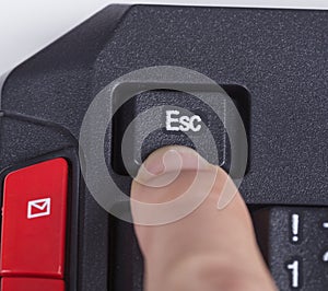 Finger pushing ESC button on keyboard of computer