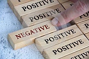 Finger pushing negative text on wooden block from the rest of the wooden blocks with positive text. Positive mindset photo