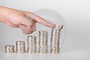 Finger pushing a pile of coins, column of coins falls , business