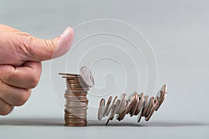 Finger pushing a pile of coins, column of coins falls , business