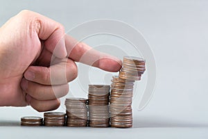 Finger pushing a pile of coins, column of coins falls , business