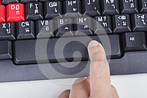 Finger pushing space bar button on keyboard of computer