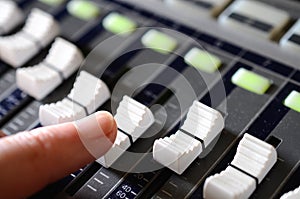 finger sliding a fader on a mixing desk.