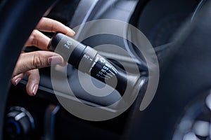 Finger is spinning a wiper control button on the car steering wheel, Close-up and Soft-focus view