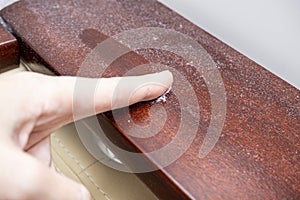 A finger swiping dust from furniture, dusty home concept