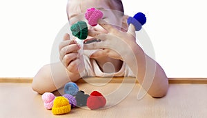 Finger toys in the hands of a little girl. A happy, cheerful girl is playing with doll knitted hats on her hands.  The baby is sit