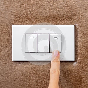 Finger turn on or off on light switch on wall at home. Energy Saving, power, electrical and lifestyle concepts