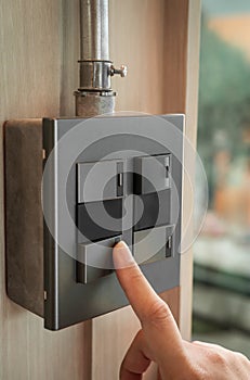 Finger is turning on a grey or black metallic light switch