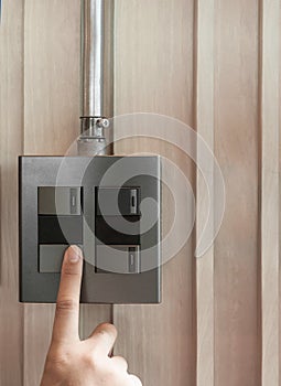 A finger is turning on a grey or black metallic light switch