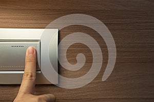 Finger is turning on a grey light switch.