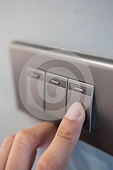 Finger is turning light switch.