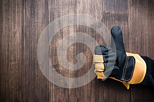 finger up gesture in construction glove close up on wooden background