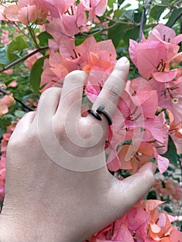 finger wearing a black ring in the shape of a bent nail with a floral background